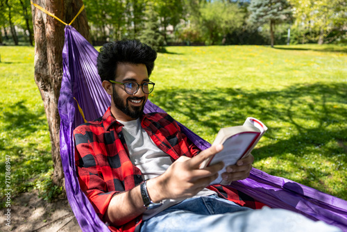 Contented young man in hammock reading a book photo