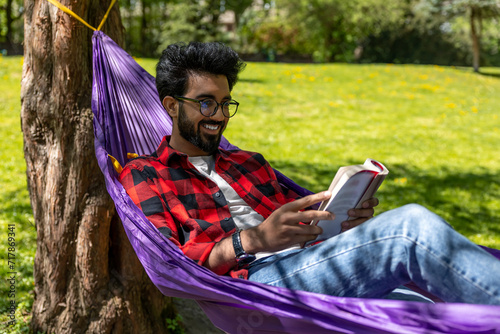 Contented young man in hammock reading a book