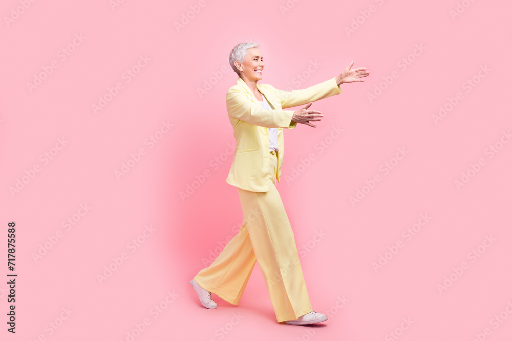 Full body photo of friendly cheerful person dressed yellow jacket stretching arms to empty space isolated on pink color background Full body photo of friendly cheerful person dressed yellow jacket stretching arms to empty space isolated on pink color background