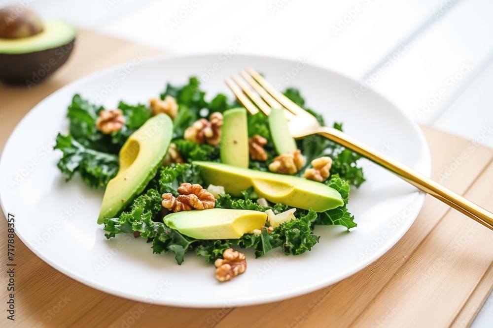 avocado chunks in a kale and walnut salad, metal fork aside avocado chunks in a kale and walnut salad, metal fork aside