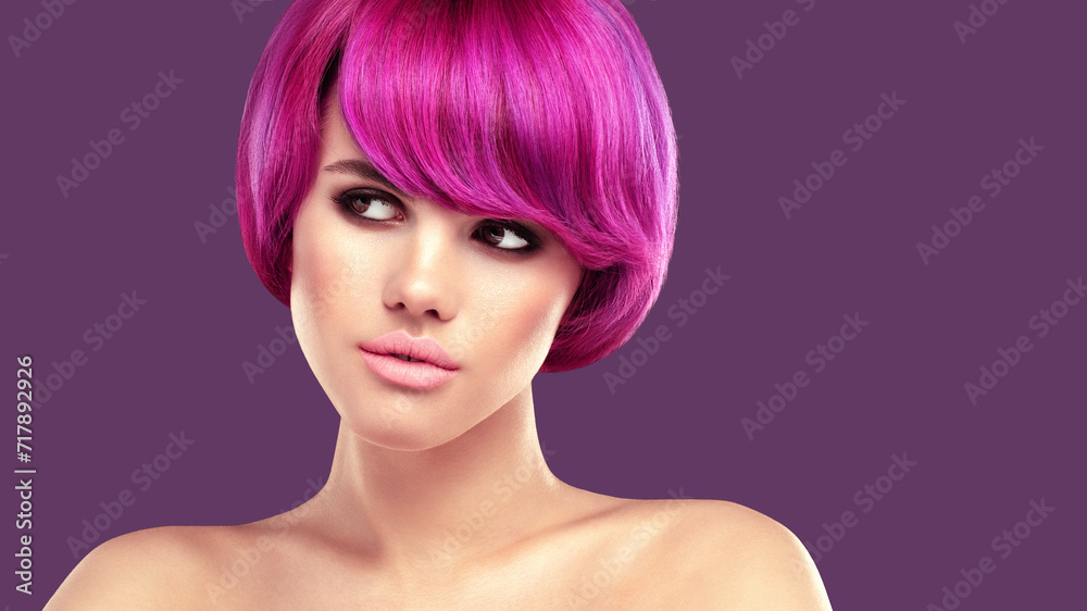 Pink hair beauty portrait. Young beautiful woman with smokey eyes make up and colorful bob hairstyle is posing against purple background.