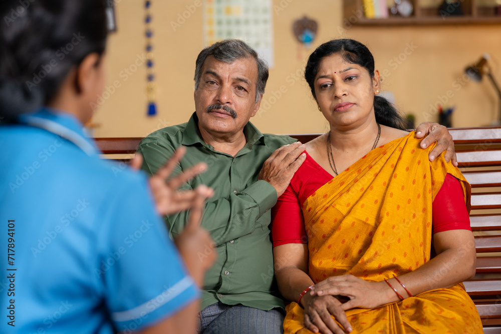 Shoulder shot of Nurse or caretaker giving advice to Senior woman while sitting with caring wife at home - concept of consultation, mental wellness and healthcare service