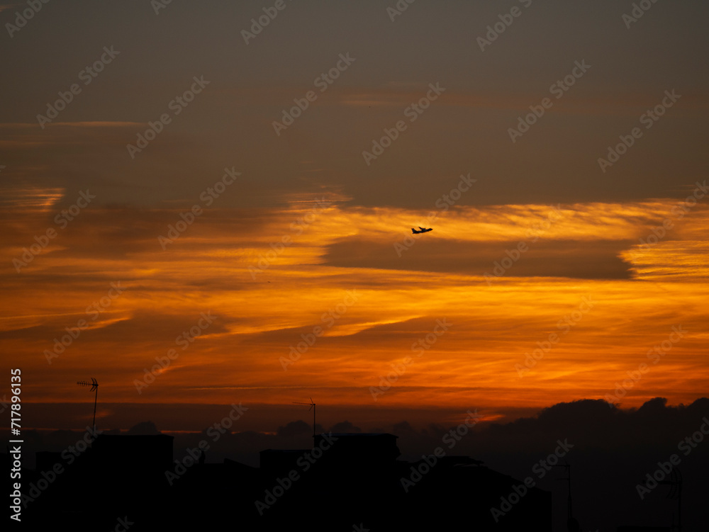 Cielo anaranjado al amanecer con avión