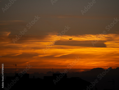 Cielo anaranjado al amanecer con avión