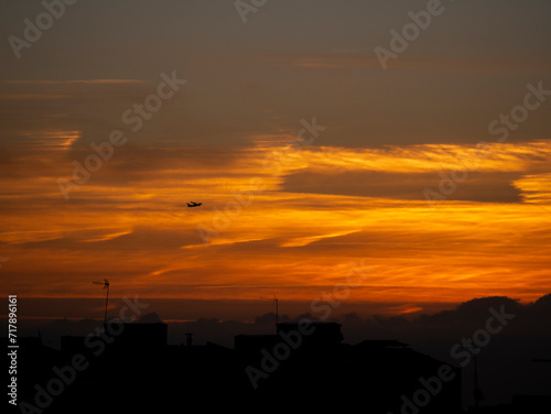 Cielo anaranjado al amanecer con avión