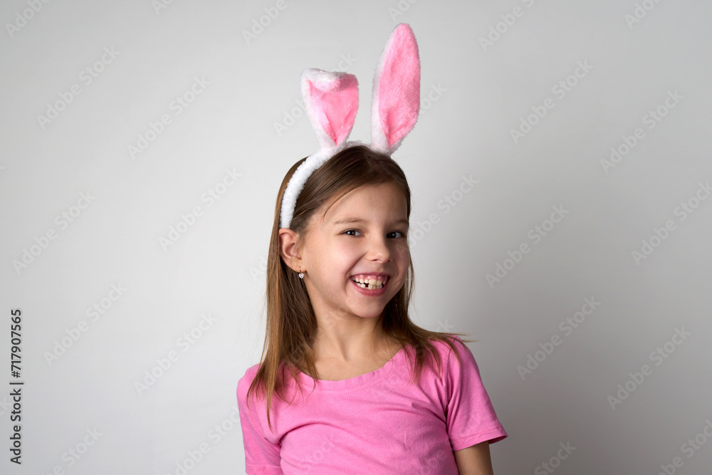Cute girl wearing bunny ears headband posing over white background