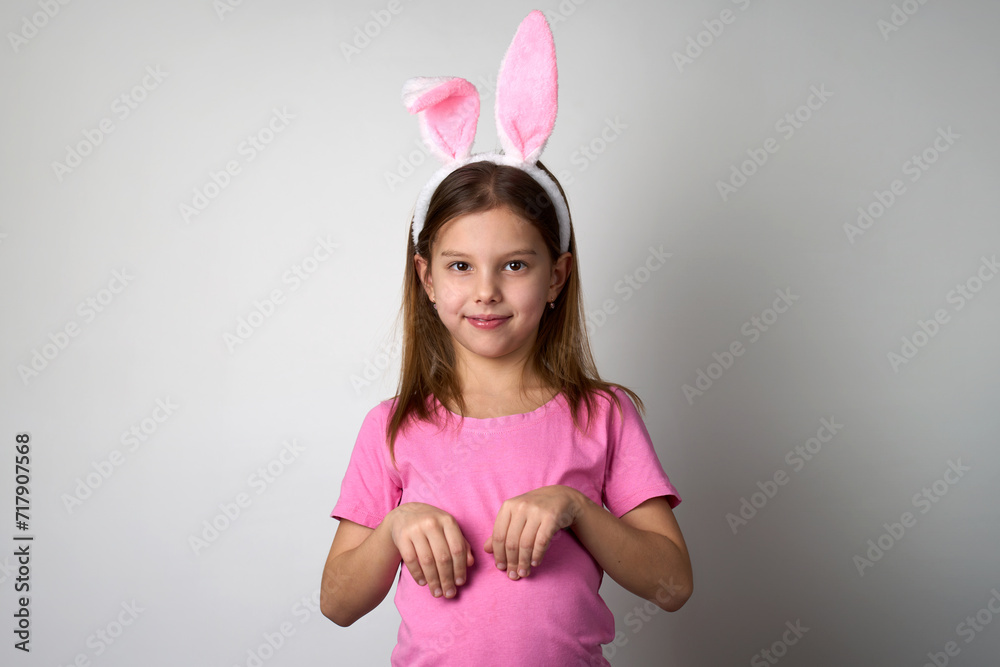 Cute girl wearing bunny ears headband posing over white background