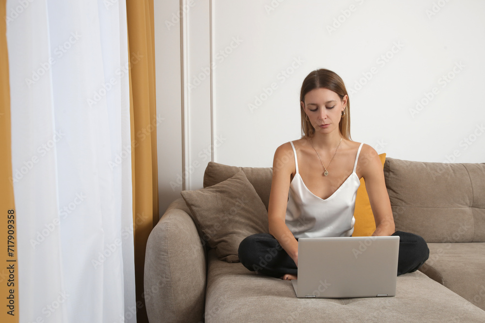 Young beautiful woman using laptop on sofa in the livingroom, working from home, internet addiction, social media, leisure time, web shopping, online education concept. Young beautiful woman using laptop on sofa in the livingroom, working from home, internet addiction, social media, leisure time, web shopping, online education concept.