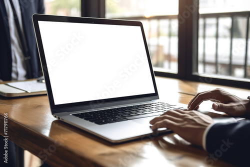 Mockup image of businessman using laptop with blank white screen on wooden table in office.