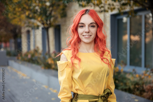 Close up portrait young red haired business and successful woman look at camera and smiling outdoor of the city sunset background.