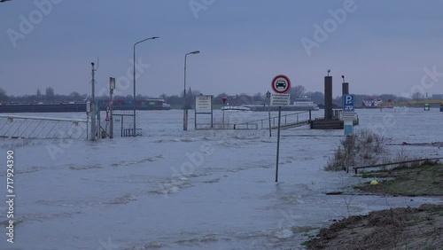 Overflown road and quay in Tolkamer, with cargo vessels and boats in the background. High water of the Rhine river in the Netherlands and Northwestern Europe. photo