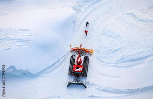 Snow groomer in white surrounding. Special vehicle preparing snow for ski jum...
