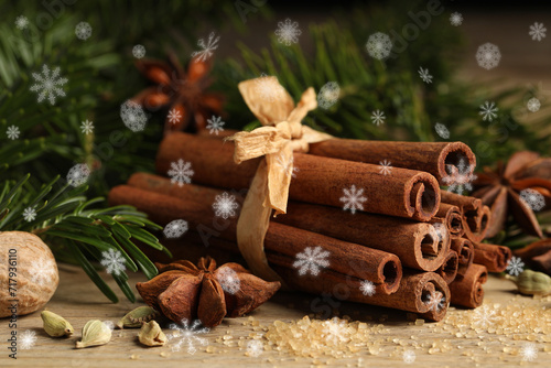 Different spices and fir tree branches on wooden table, closeup. Cinnamon, anise, cardamom, nutmeg