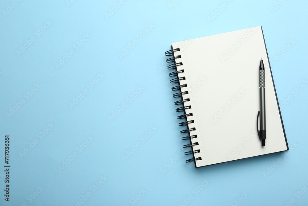 Notebook and pen on light blue background, top view. Space for text Notebook and pen on light blue background, top view. Space for text