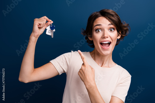 Photo portrait of pretty young girl point excited keychain wear trendy white clothes isolated on dark blue color background
