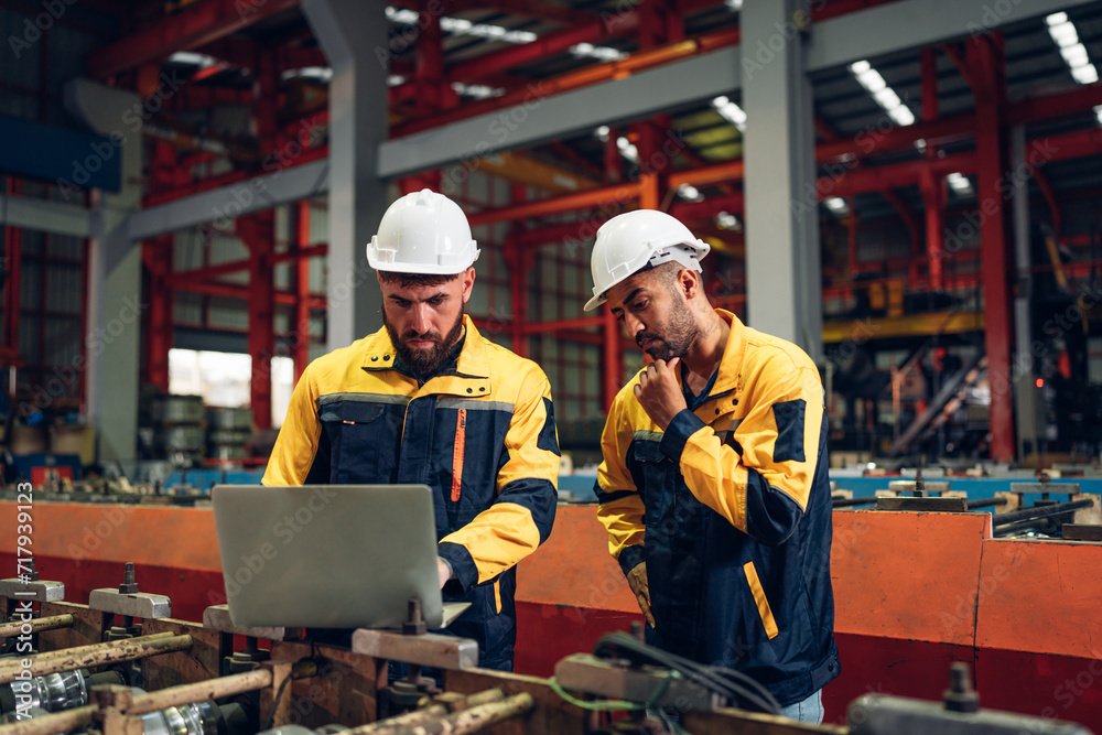 Industrial man engineer wear uniform and helmet using laptop are checking system machine at factory. Workers industrial factory. Machine maintenance technician operation concept. Industrial man engineer wear uniform and helmet using laptop are checking system machine at factory. Workers industrial factory. Machine maintenance technician operation concept.