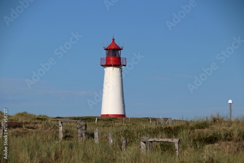 Ellenbogen lighthouse on sand dune against blue sky with white clouds on northern coast of Sylt island, Germany