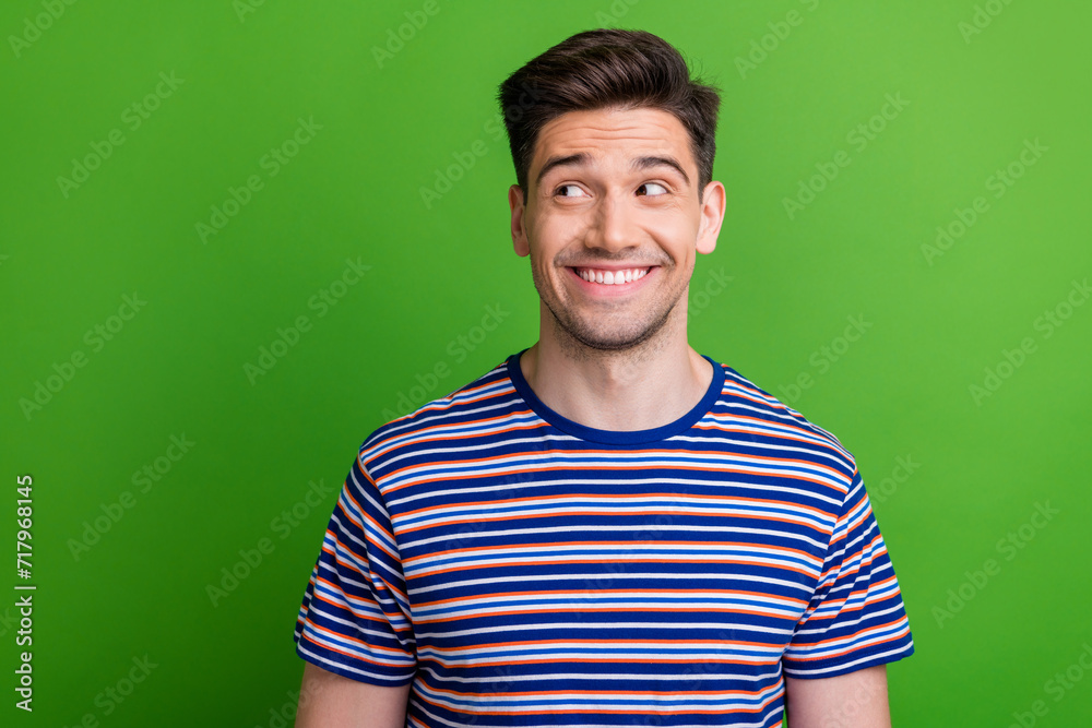 Portrait of positive creative minded person beaming smile look interested empty space isolated on green color background Portrait of positive creative minded person beaming smile look interested empty space isolated on green color background