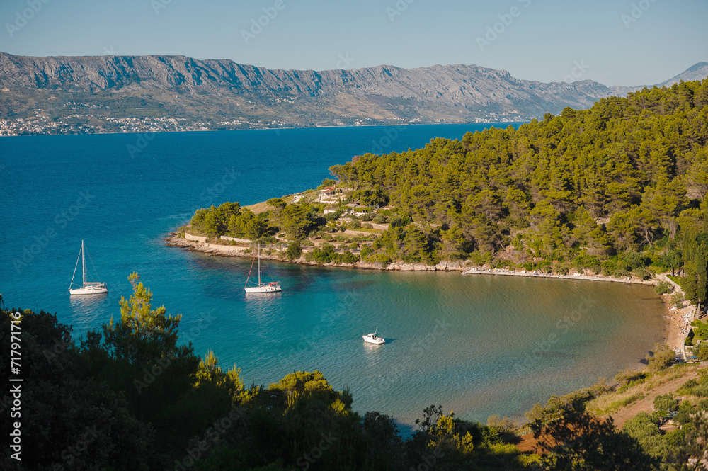 Top view of tranquil bay in Brac island with motor yachts and residential buildings. Green nature and rocky mountains around. Beautiful landscapes in Croatia.
