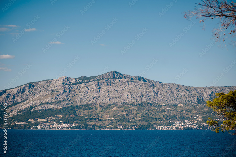 Deep sea stretching out in front of high mountains and creating beautiful contrast between blue water and majestic rocky peaks. Picturesque scenery of Brac island, Croatia.