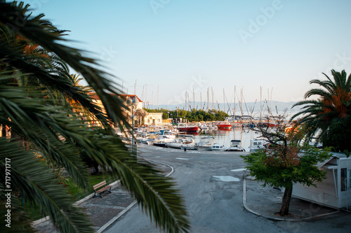 Fototapeta Naklejka Na Ścianę i Meble -  Front view of deserted pedestrian asphalt street near small pier with many moored ships. Picturesque landscape of city Supetar, Croatia. Concept of architecture and summertime.