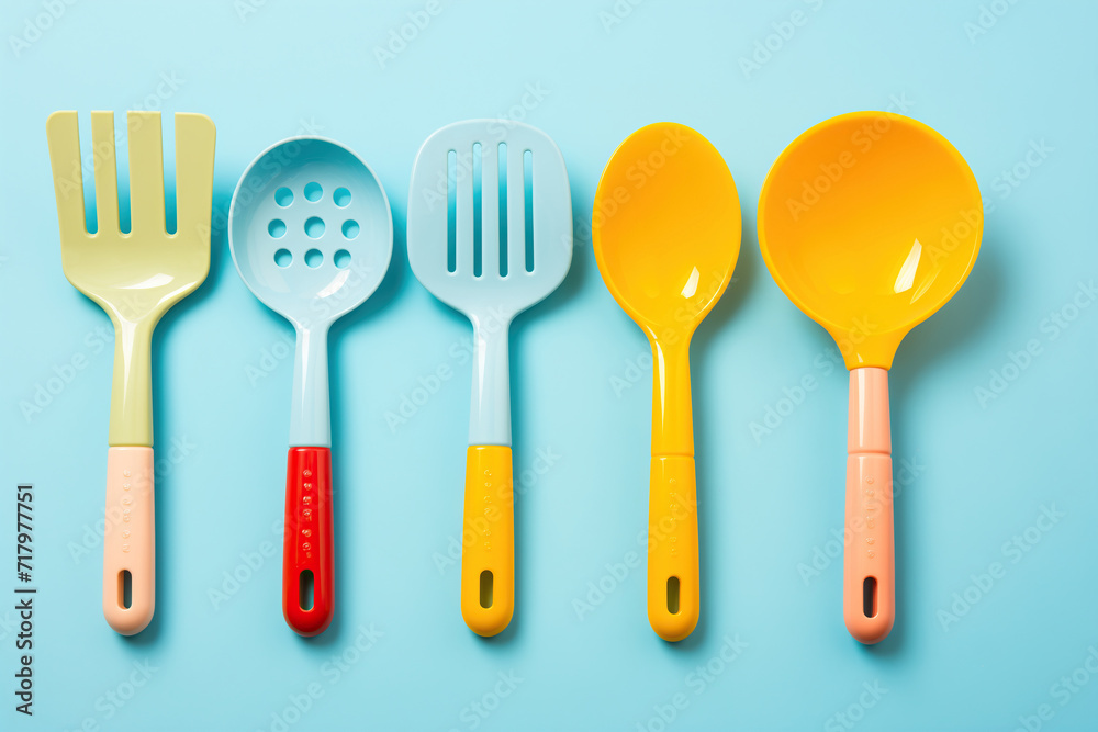 Vibrantly Colored Kitchen Utensils Lined Up on a Pastel Blue Background. Flat Lay Top View Creative Color Design Concept Vibrantly Colored Kitchen Utensils Lined Up on a Pastel Blue Background. Flat Lay Top View Creative Color Design Concept