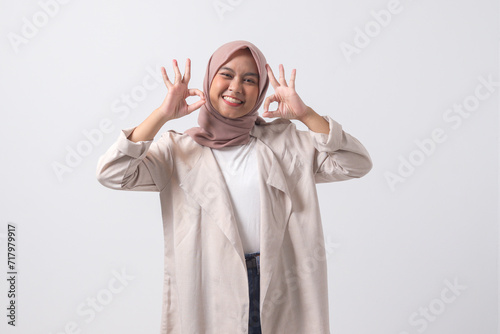 Portrait of excited Asian hijab woman in casual suit showing ok hand gesture and smiling looking at camera. Advertising concept. Isolated image on white background