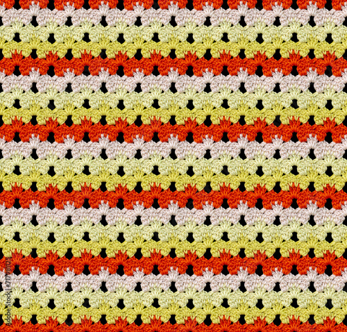 Seamless knitted texture in floral style. The pattern is crocheted from multicolored cotton yarn. Yellow-orange color combination.