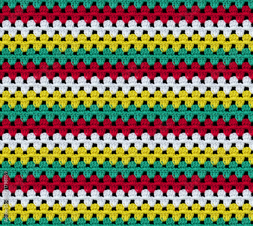 Bright seamless knitted texture. The pattern is crocheted from multi-colored cotton yarn. Zigzag shapes. African motives. 