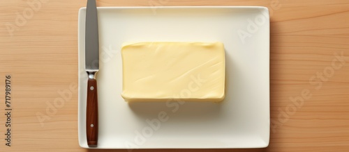 A block of butter, perfectly sliced with a knife, sits on a pristine plate, perfectly arranged, shot from above, leaving ample space for text.