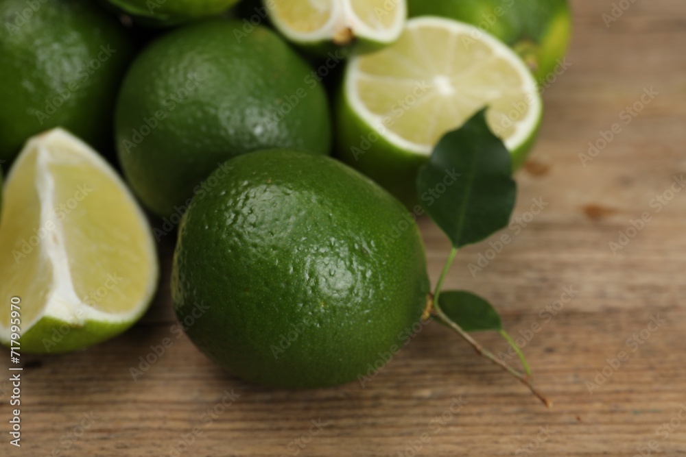 Fresh limes and leaves on wooden table, closeup