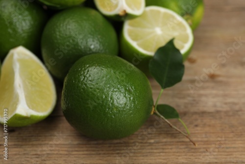 Fresh limes and leaves on wooden table  closeup