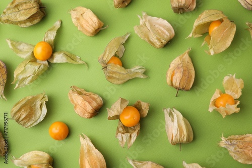 Ripe physalis fruits with calyxes on light green table, flat lay