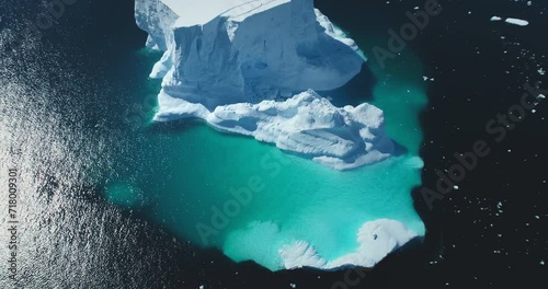 Huge iceberg floating in turquoise frozen ocean water. Antarctica majestic melting glacier landscape, polar scene background. Beauty wild untouched nature. Cinematic aerial top view rotation panorama