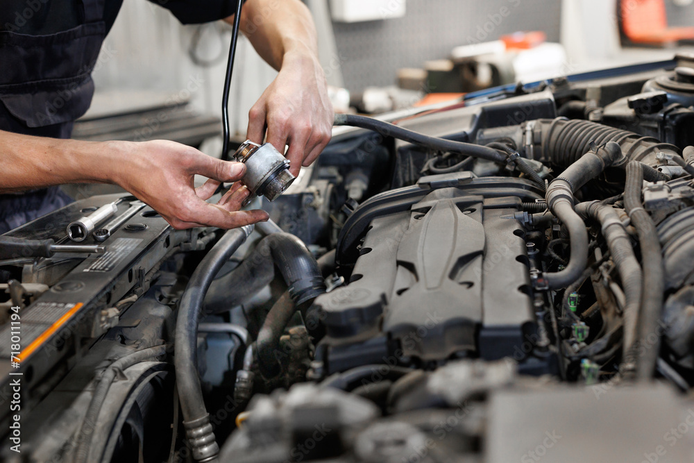 Close-up of a worker, a repairman, repairing a car. The open hood of the car in the repair garage. Close-up of a worker, a repairman, repairing a car. The open hood of the car in the repair garage.
