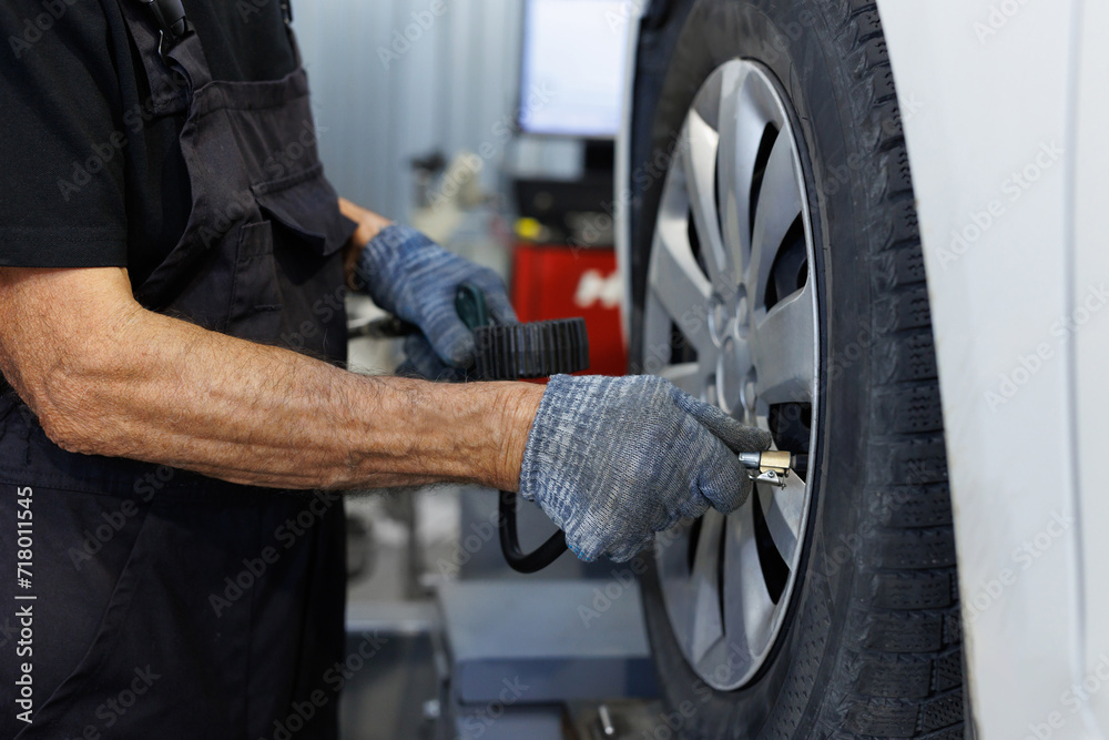Close up mechanic inflating tire and checking air pressure with gauge pressure in service station. Close up mechanic inflating tire and checking air pressure with gauge pressure in service station.