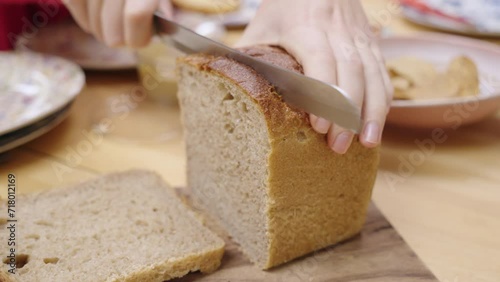 Cutting a slice of bread using a sharp breadknife at the dinner table. photo