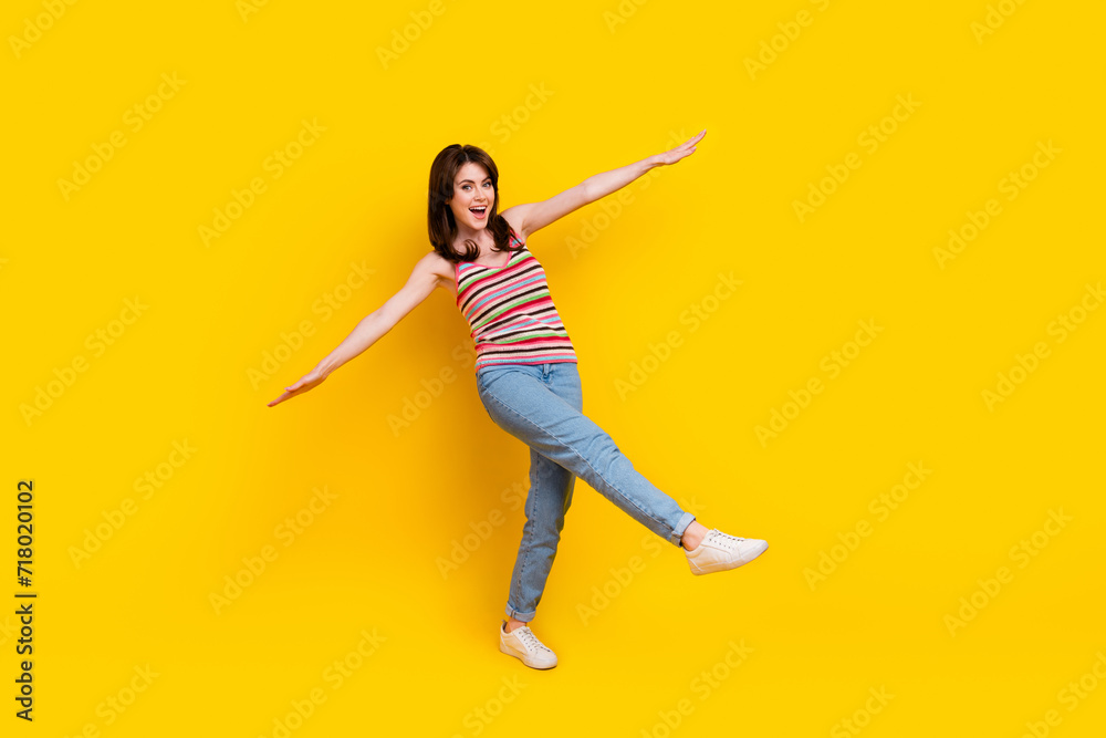 Full size photo of pretty adorable woman dressed knitwear top jeans pants holding palms like wings isolated on yellow color background Full size photo of pretty adorable woman dressed knitwear top jeans pants holding palms like wings isolated on yellow color background