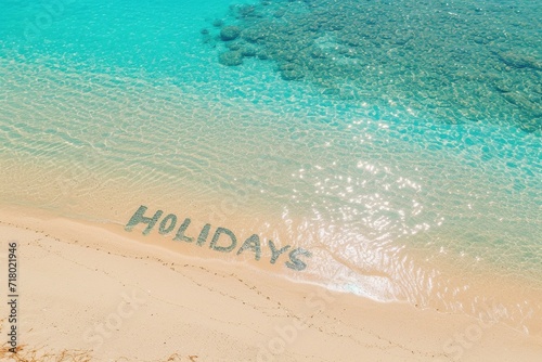 A breathtaking aerial view of the word "HOLIDAYS" etched into a golden sandy beach, overlooking a crystal-clear sea