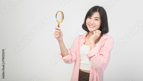 Young asian woman holding magnifying glass over white background, analysis and finance concept.