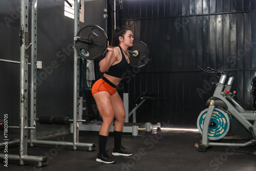 Fitness girl about to perform a barbell squat in the gym.