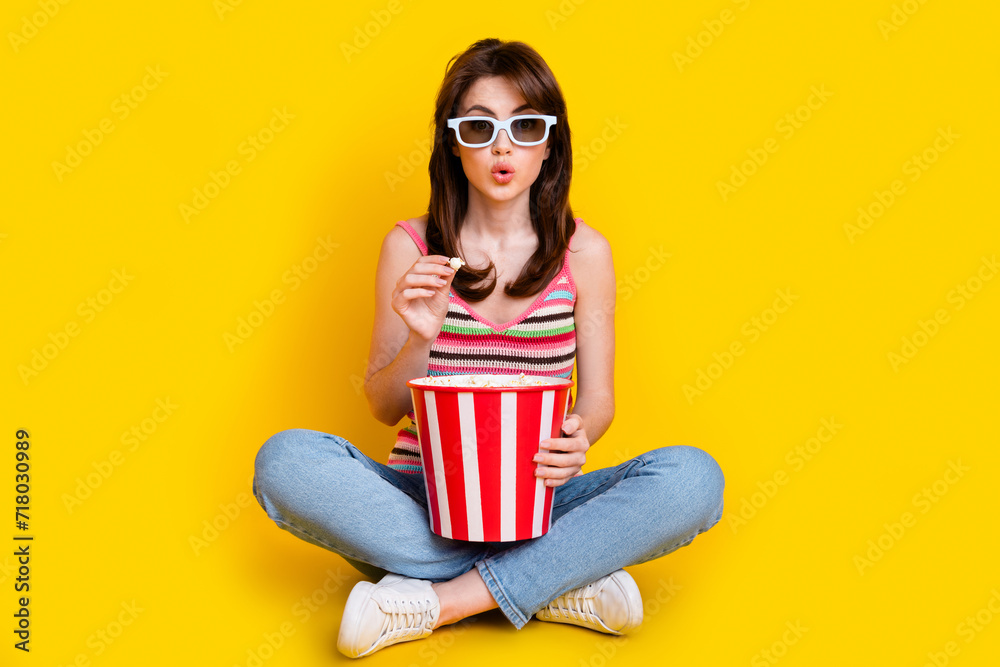 Obraz premium Full body photo of stunned girl wear knit tank in 3d glasses sit hold popcorn watch interesting movie isolated on yellow color background