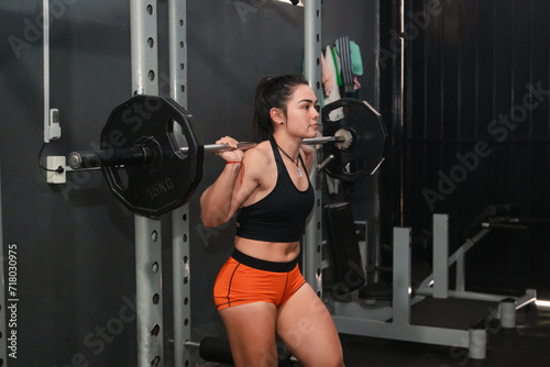 Fitness girl preparing to do a barbell squat in the gym.