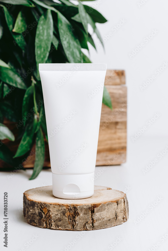 White cosmetic tube for facial cream on wooden podium, green plant leaves at the background. Natural eco friendly skincare, body lotion, face cream. Template for beauty products, neutral aesthetics White cosmetic tube for facial cream on wooden podium, green plant leaves at the background. Natural eco friendly skincare, body lotion, face cream. Template for beauty products, neutral aesthetics