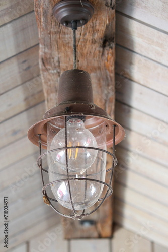 Big bulb with glass cover hanging from a wooden ceiling © Luaa