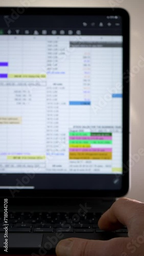 Vertical video social media format – Closeup of a hand using a laptop or tablet keyboard to scroll through data in a spreadsheet app on a screen display.