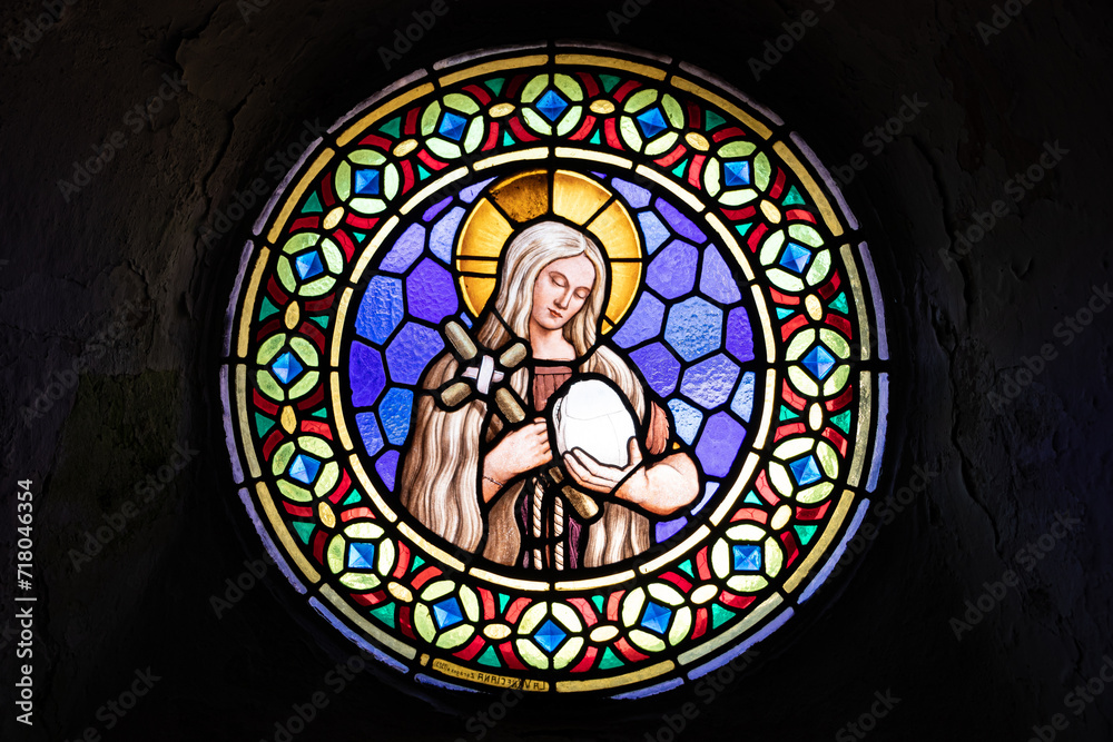 A Ponte Ulla, Spain. Stained glass window representing Saint Mary Magdalene holding cross and a a human skull