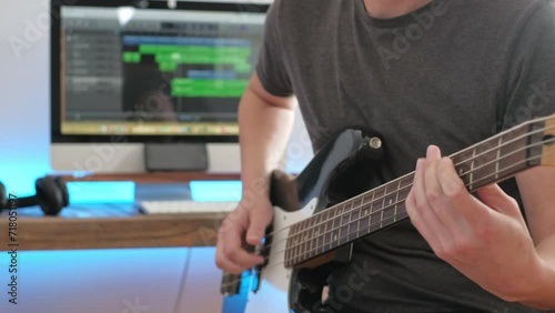 a medium shot of a man playing guitar solos, chords and rhythm with bass in a studio focussing on the hands photo