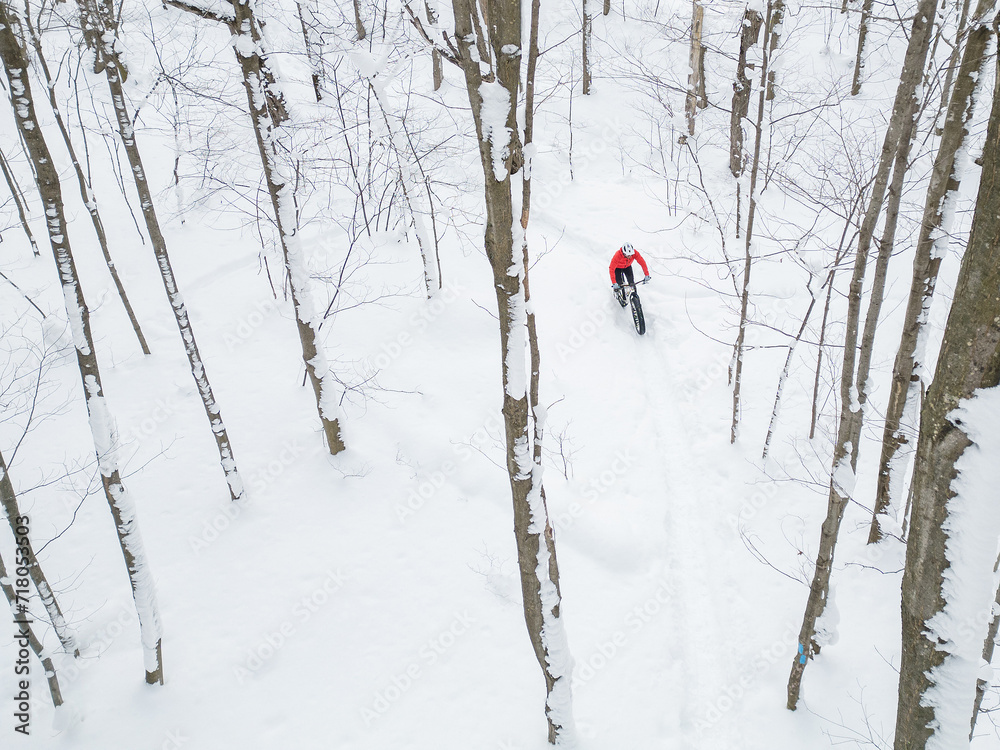 Drone view of a fat biker riding his bicycle in the snow during Canadian winter