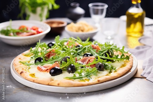 thincrust pizza with olives and arugula on a stone backdrop